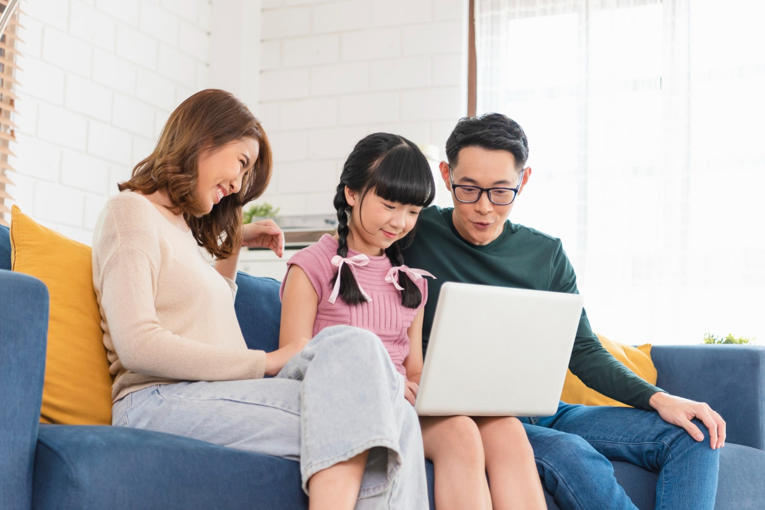 Happy Asian Family Using Laptop Sitting On A Couch 